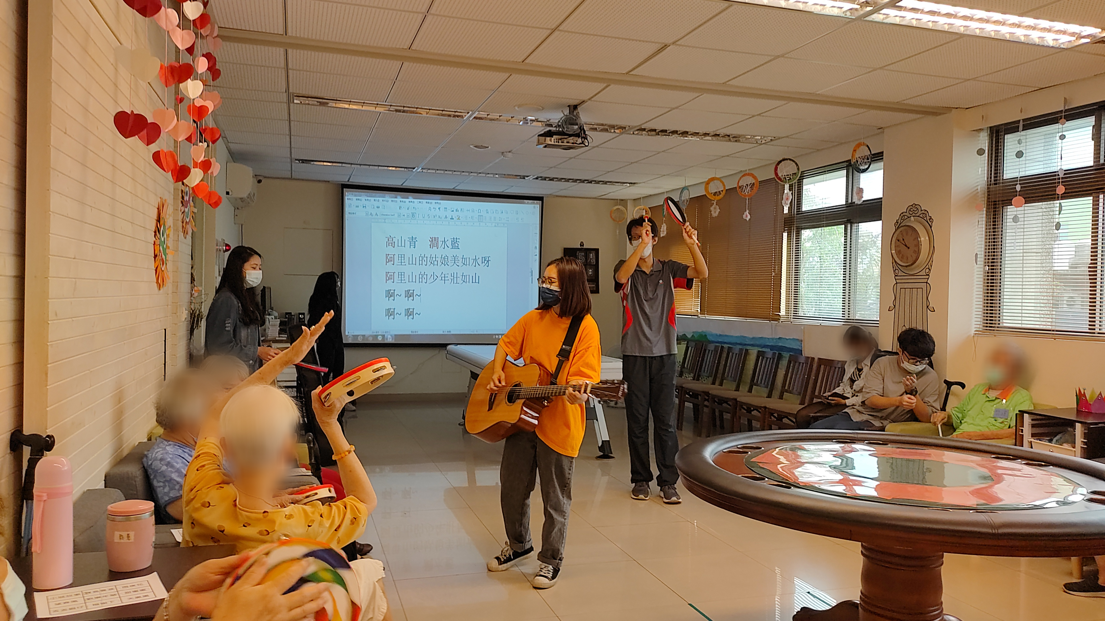 參加音樂治療工作坊的亞大學生至失智老人據點，運用課程所學，帶領高齡者玩起鈴鼓，接受音樂治療。