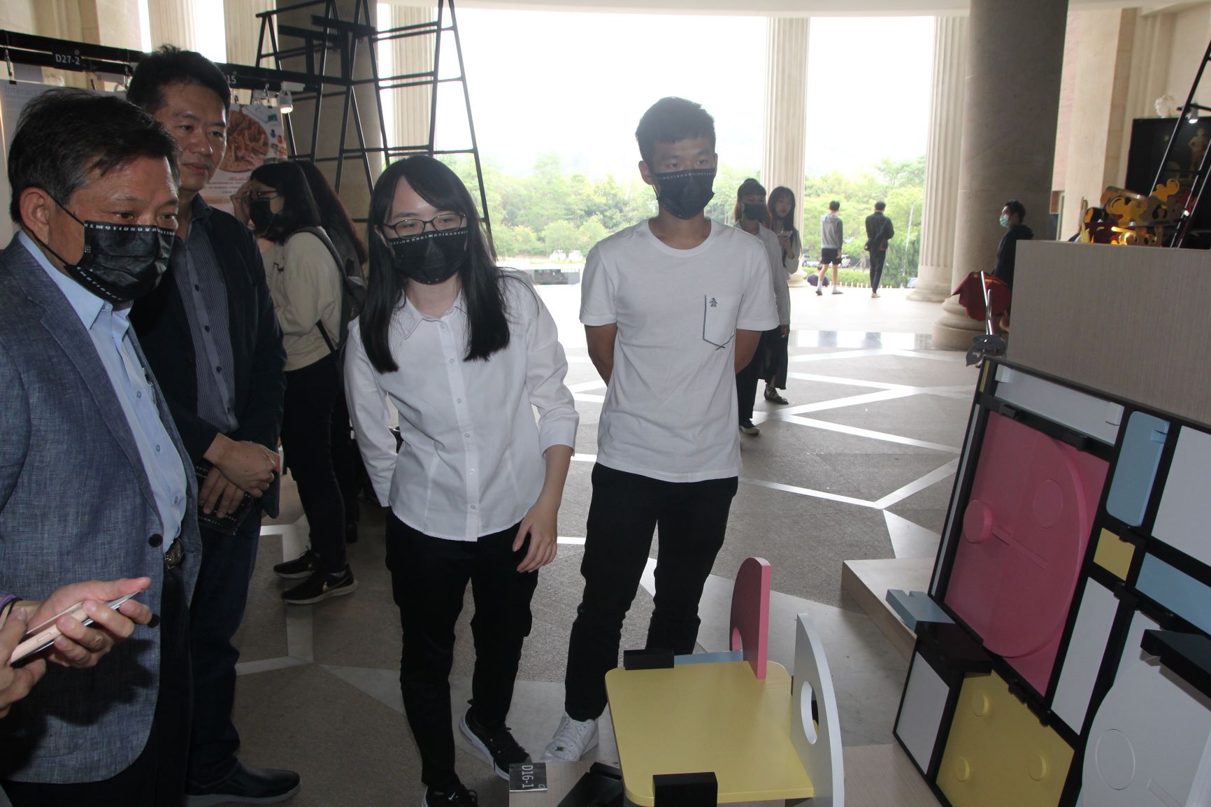 中新科技公司董事長江舟陣（左）在商設系主任林信宏(左2)陪同下，聽取學生解說設計理念。