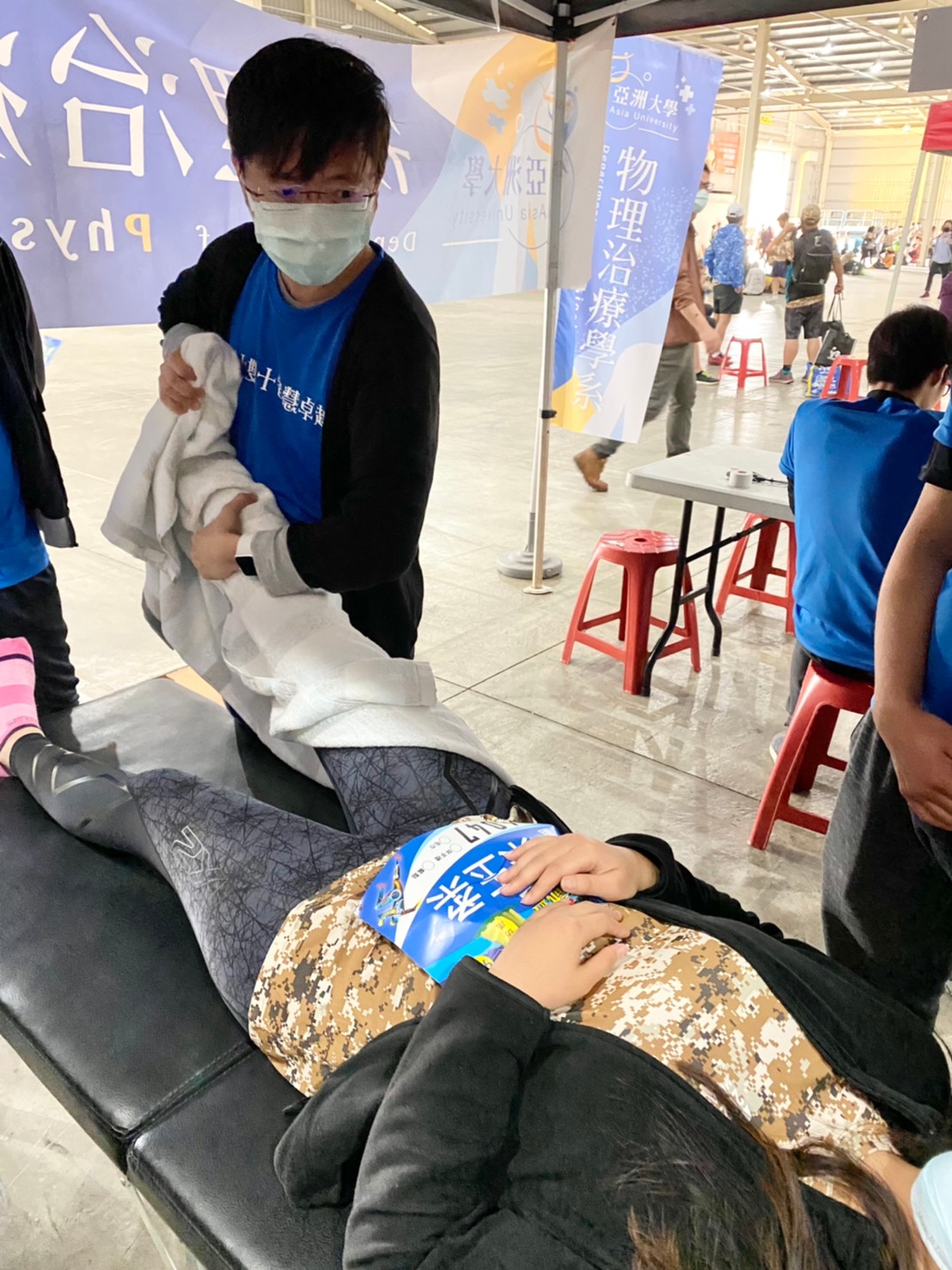 亞大物治系老師陳彥年，協助跑完馬拉松比賽的跑者，緩解賽後小腿抽筋問題。