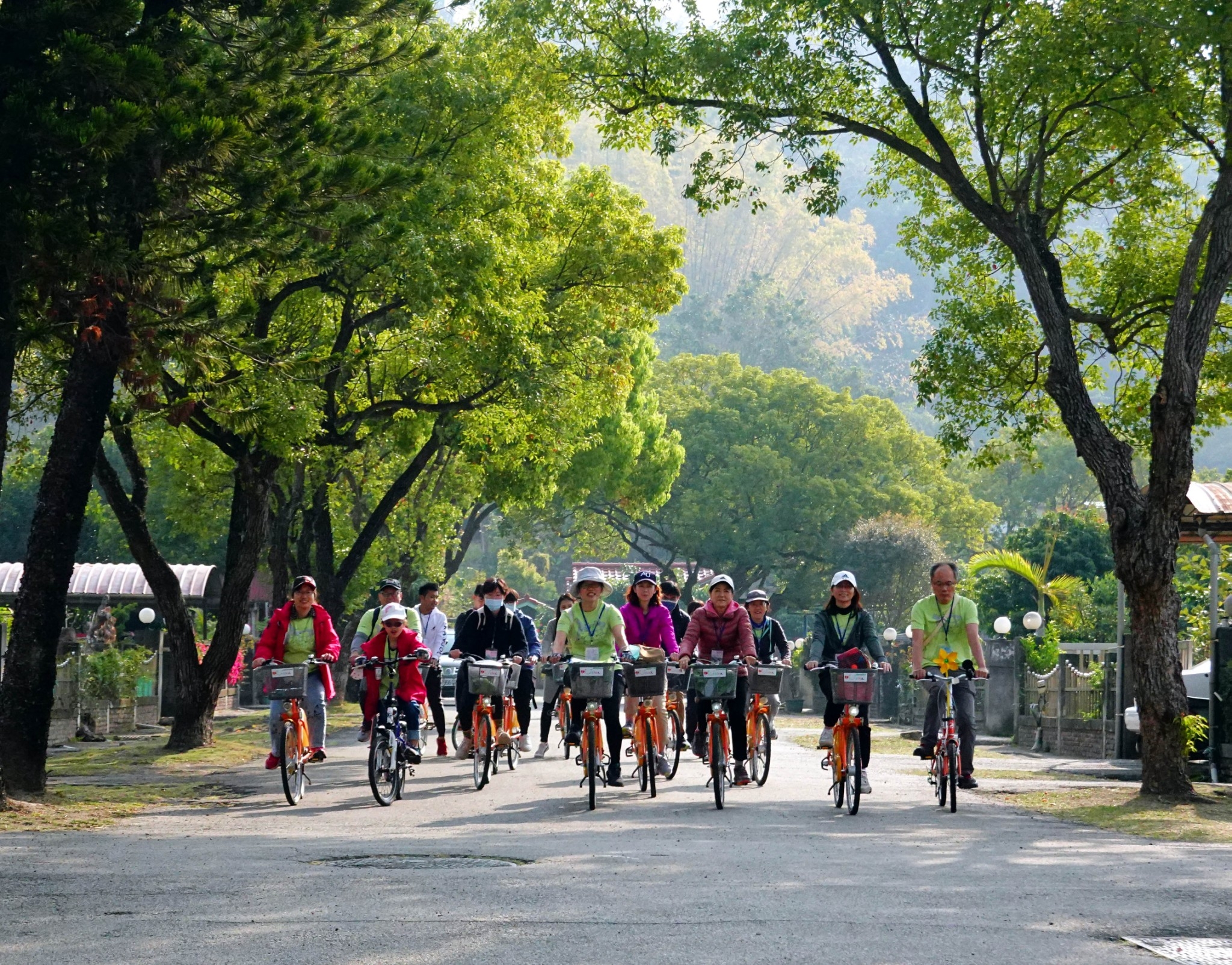 亞大通識中心黃淑貞主任(前左4)與校友、師生20人，單車繞騎霧峰，行經老樹成蔭的光復新村。
