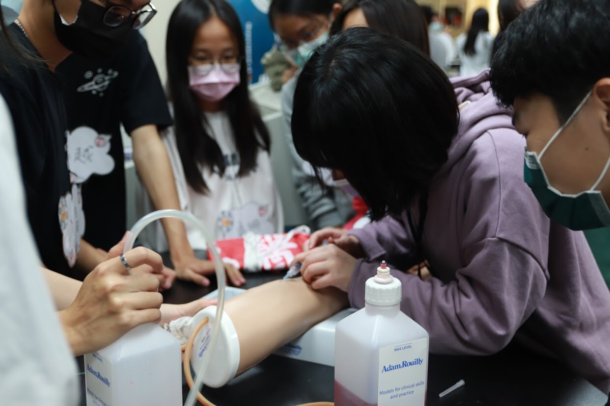 參加「第一屆亞大醫技營」的高中生們以抽血手臂練習抽血。