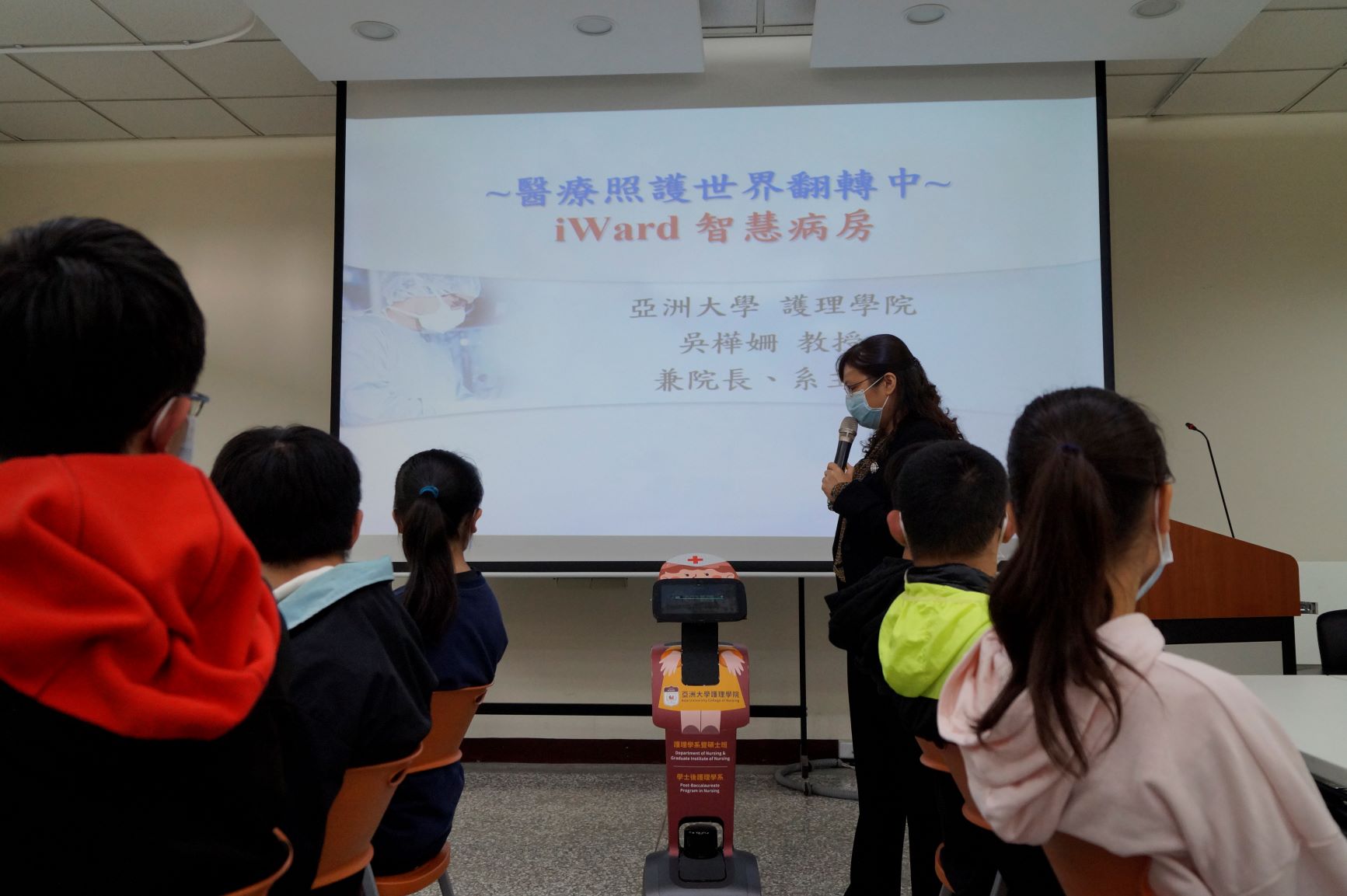 亞大「AI醫療營隊」的學員們，1月31日上午參觀護理學院，看到吳樺姍院長（站立者）與Temi照護機器人進行語音互動，都覺得十分有趣。