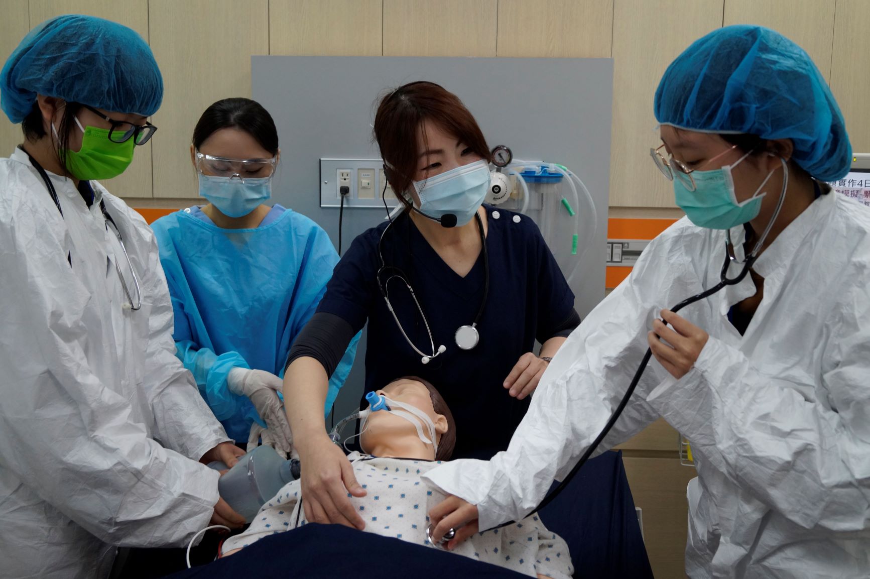 亞大護理學系彭逸稘老師（中），利用智慧高階模擬人，設定緊急救護擬真情境，讓學員們（左、右戴藍色帽子者）體驗。