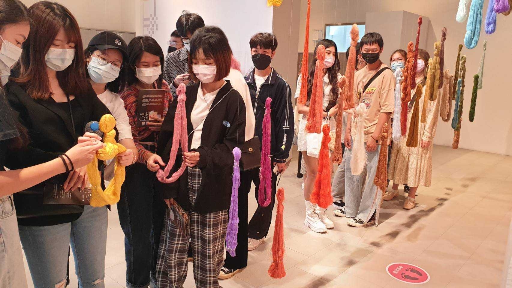 學生們參觀「歲時經緯-人間國寶邀請展」，觸摸蠶絲織物體驗。