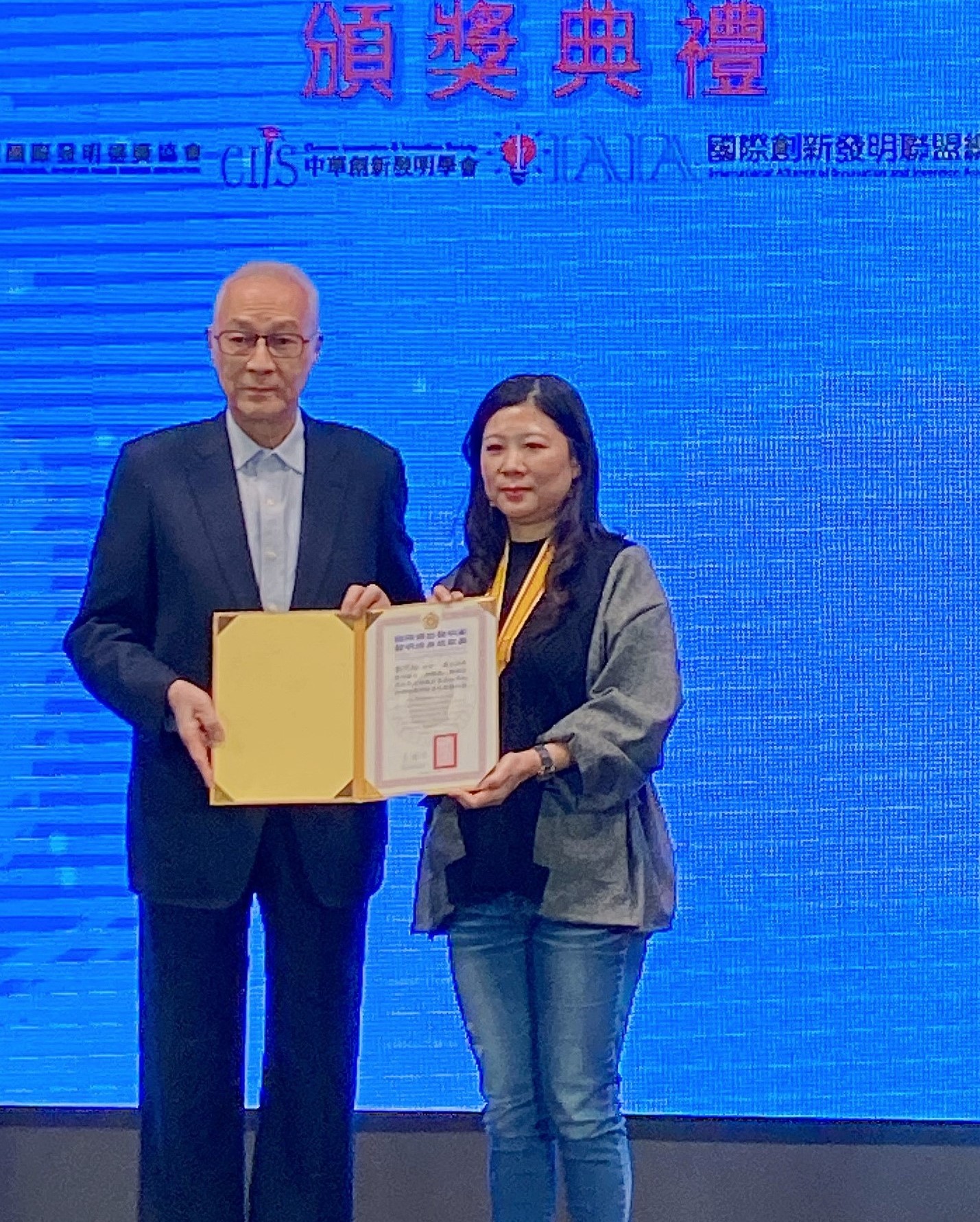前副總統吳敦義(左)頒發國際傑出發明家終身成就獎，給亞大設計學院助理教授劉芃均。