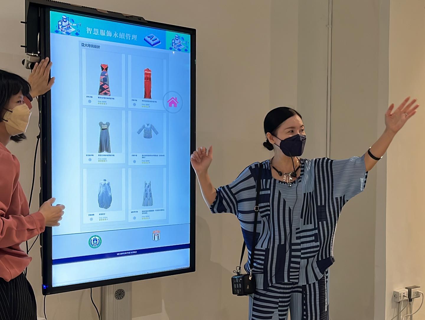 時尚系主任林青玫(右)解說「虛擬試衣間」，民眾站在螢幕前，任選衣物，就可看到試穿的效果
