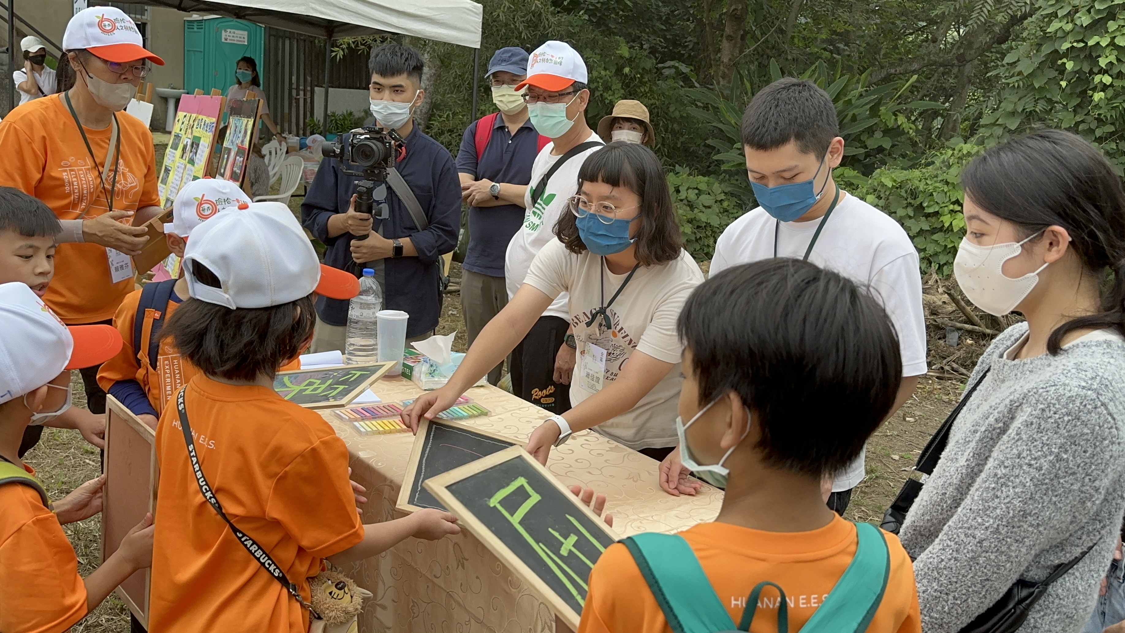 圖為亞大同學在華南實驗國小60週年校慶活動中，協助小朋友玩闖關遊戲。