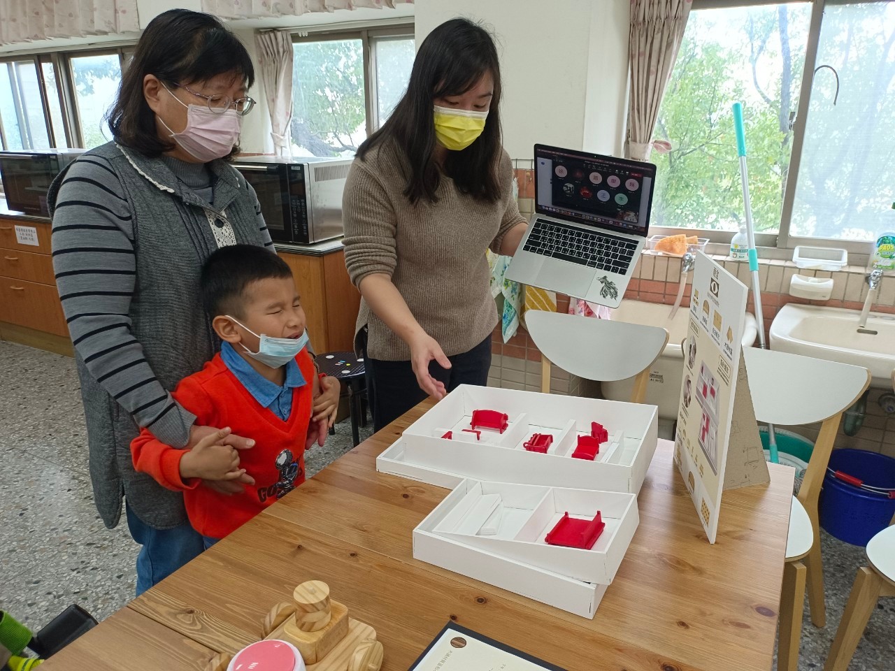 图为惠明盲校老师卞秀枝(左)、亚大商设系老师王静仪(右),共同评比同学的视障幼儿教具。