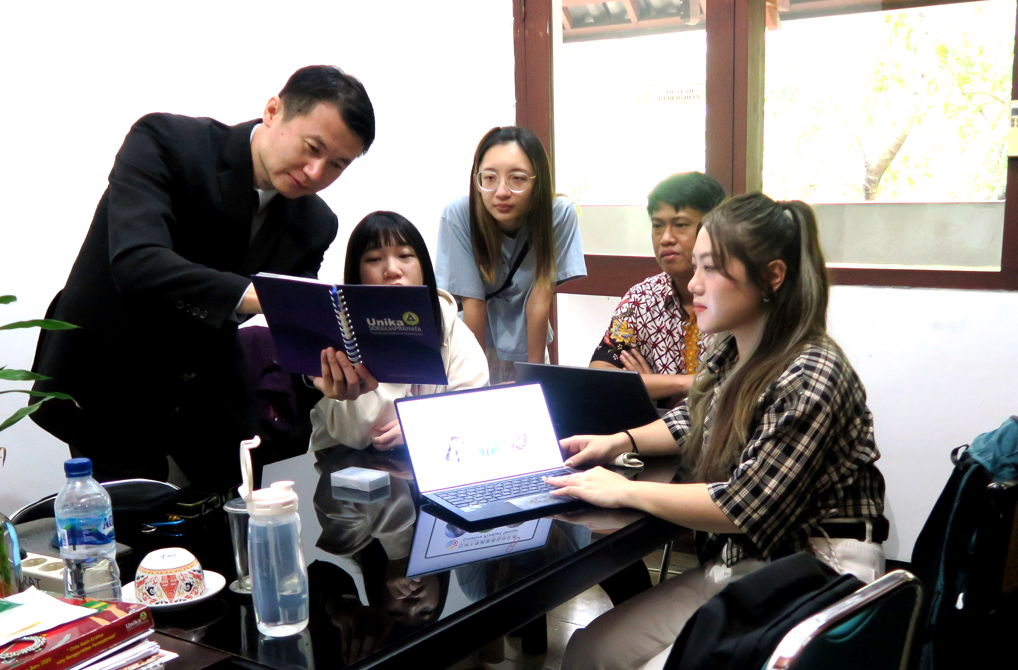 图为亚大商设系主任龙希文 (左1)，印尼三宝垄天主教总督大学国际长Peter Ardhianto  (左4)，与3位亚大实习同学高会评、张馨云、蔡昀庭(由左而右)，一同讨论设计案。