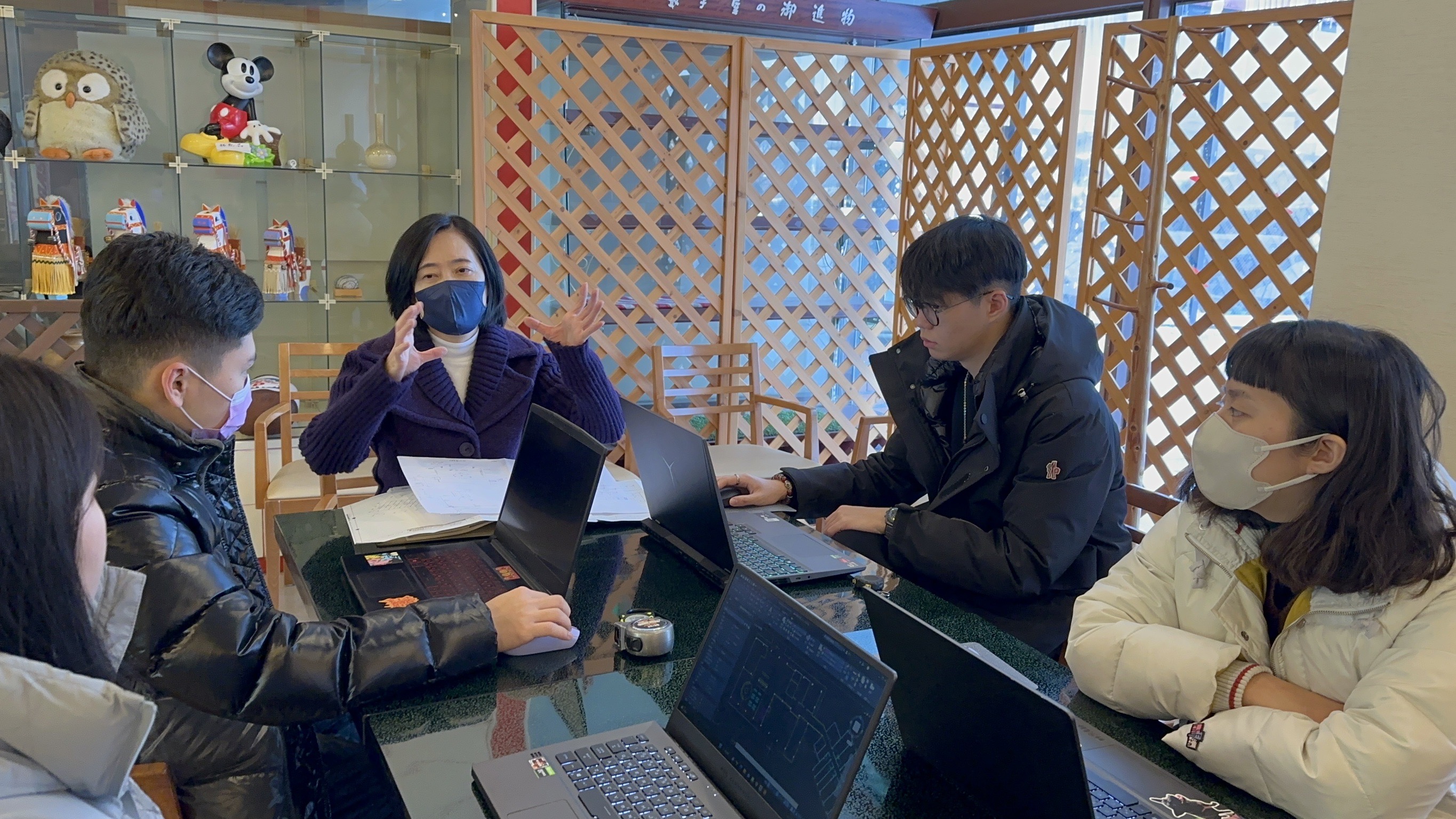 圖為亞大室設系老師林佳慧(中)，與4位研習同學討論飯店設計。