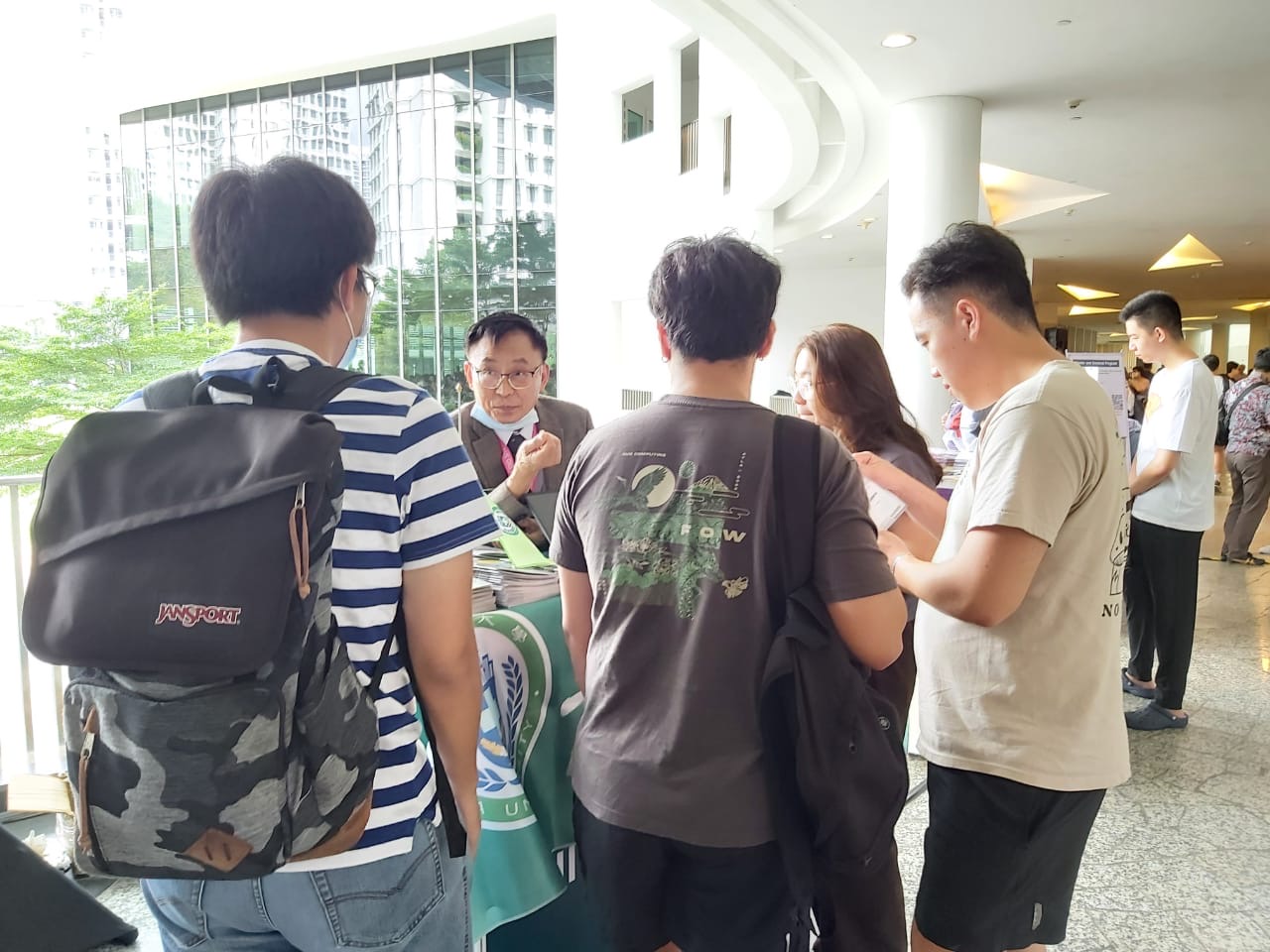 圖為亞大國際學院長陳英輝(左2)，在國立新加坡大學的夏日學校博覽會，向該校學生說明亞大暑期課程。