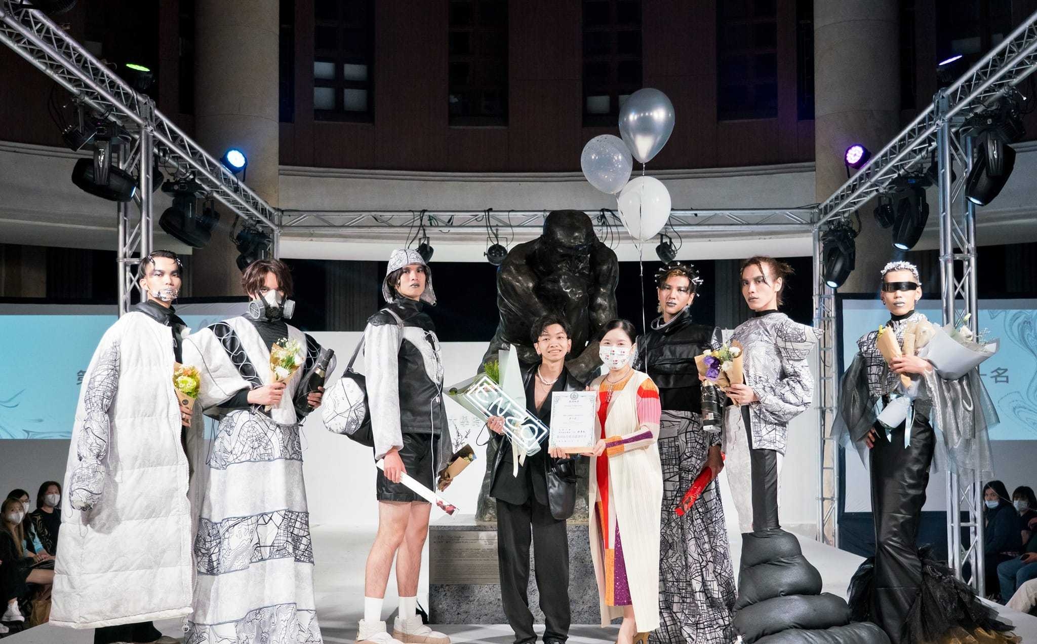 圖為亞大時尚系主任林青玫(右4)，頒獎給服裝組高行佑同學(右5)，他的作品「同溫層 echo chamber」，獲第1名。