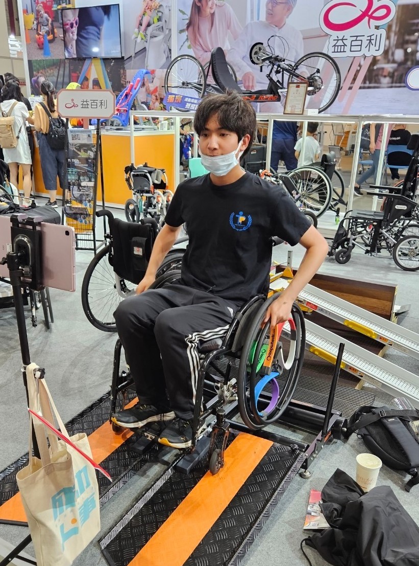 圖為亞大物治系同學，在輔具展中體驗測速輪椅。