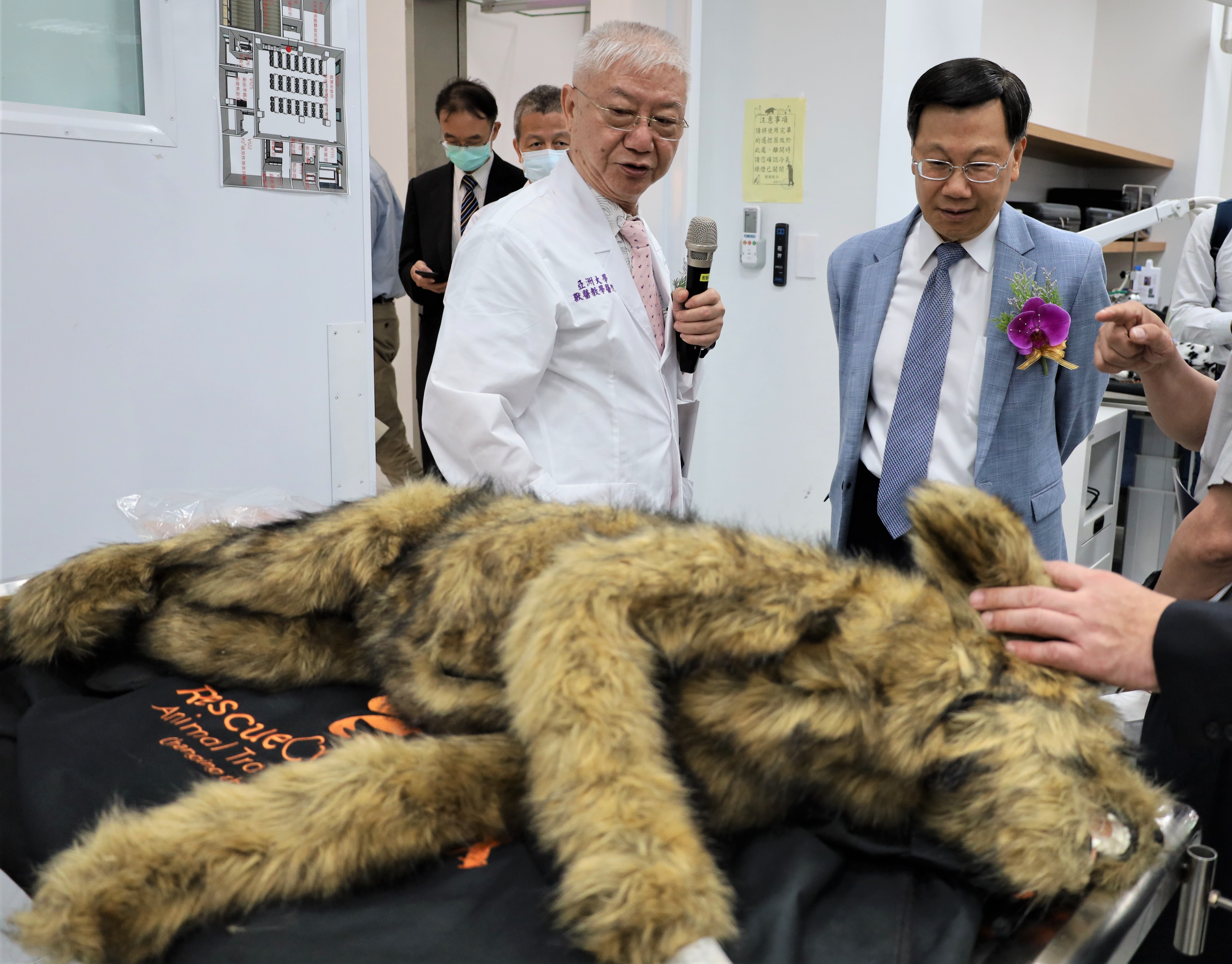 图为亚大校长蔡进发(右)，经学士后兽医系主任简基宪介绍设备，对亚大附属兽医院采用「安妮狗」，十分感兴趣。