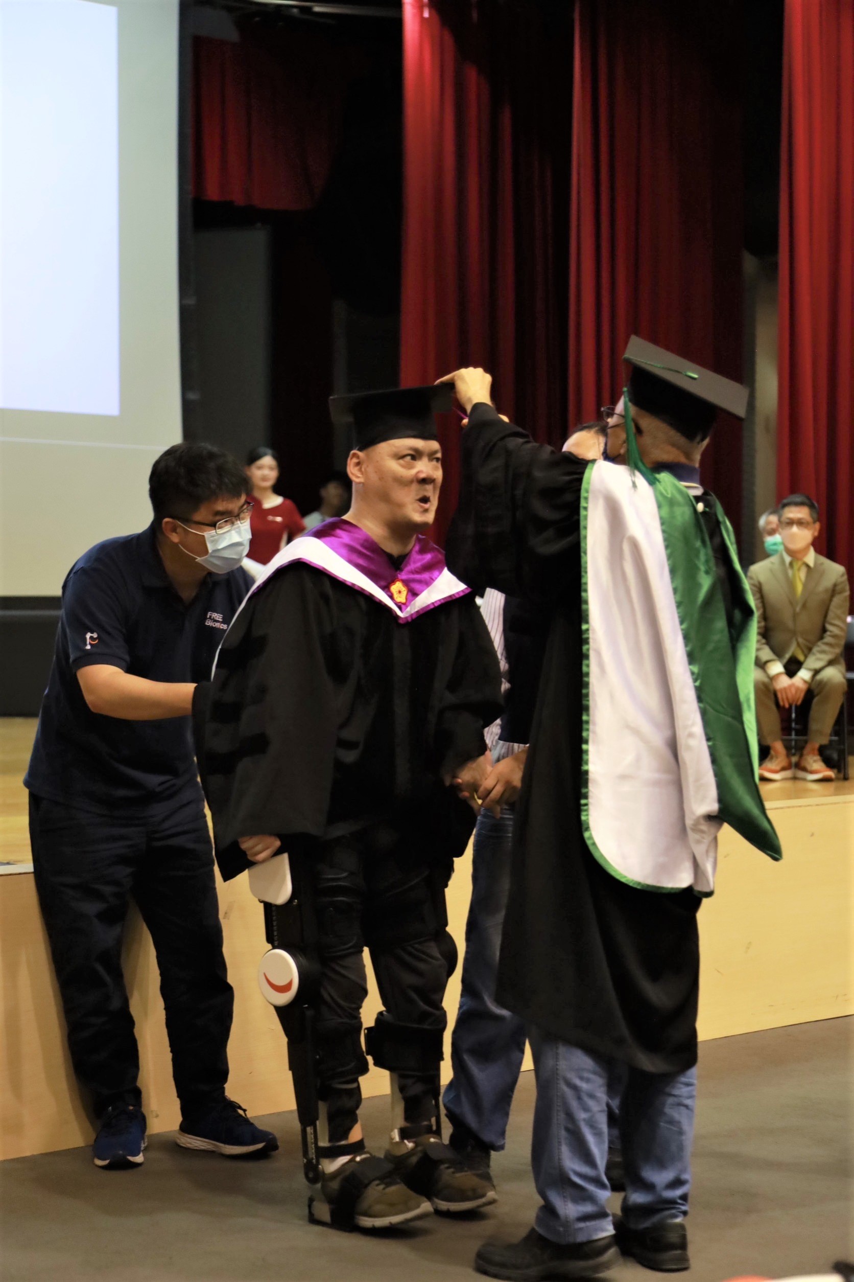 圖為亞大畢業典禮上，副校長吳聰能(右)代表，為腦麻博士生陳銘哲(中)撥穗，祝賀他畢業。