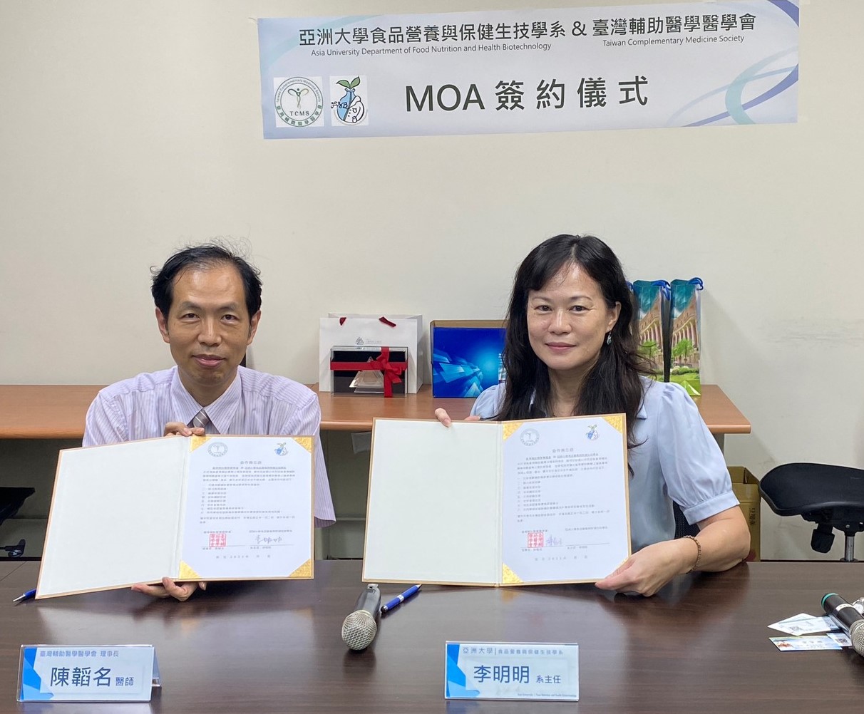 The image shows Li Mingming (李明明), chairwoman of the Department of Food Nutrition and Health Biotechnology (right) and Chen Tao Ming(陳韜名), President of the Taiwan Complementary Medicine Society, signing a MOA.