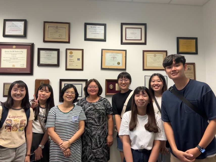 The image shows Professor Lei-shih Chen at Texas A&M University (3rd from the left) taking a group photo with the interns from the Department of Healthcare Administration at Asia University.