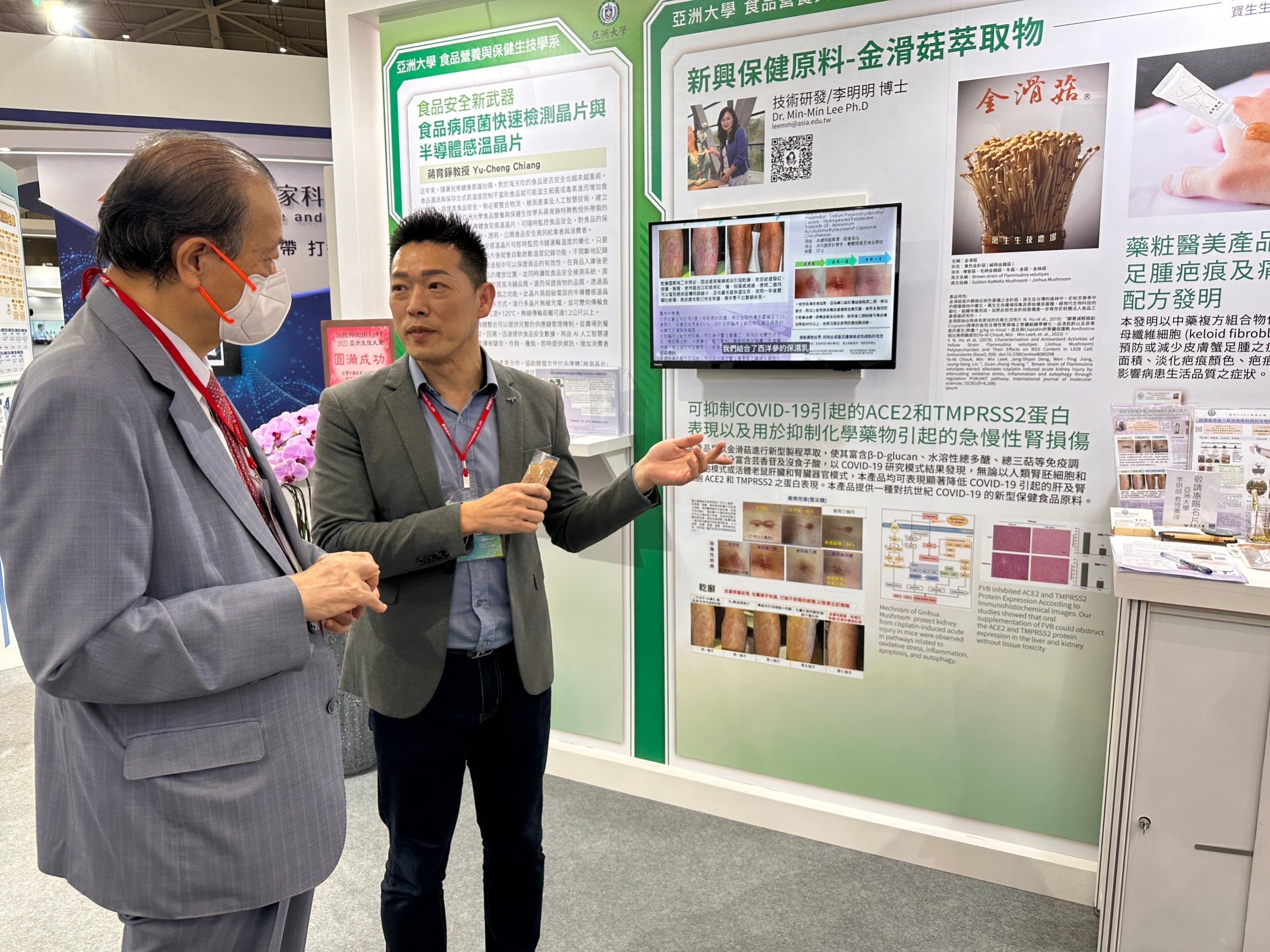 圖為亞大創辦人蔡長海博士(左)在「2023亞洲生技大展」現場，聆聽亞大研究生吳文良解說「改善蟹足腫疤痕的配方產品」研究成效。