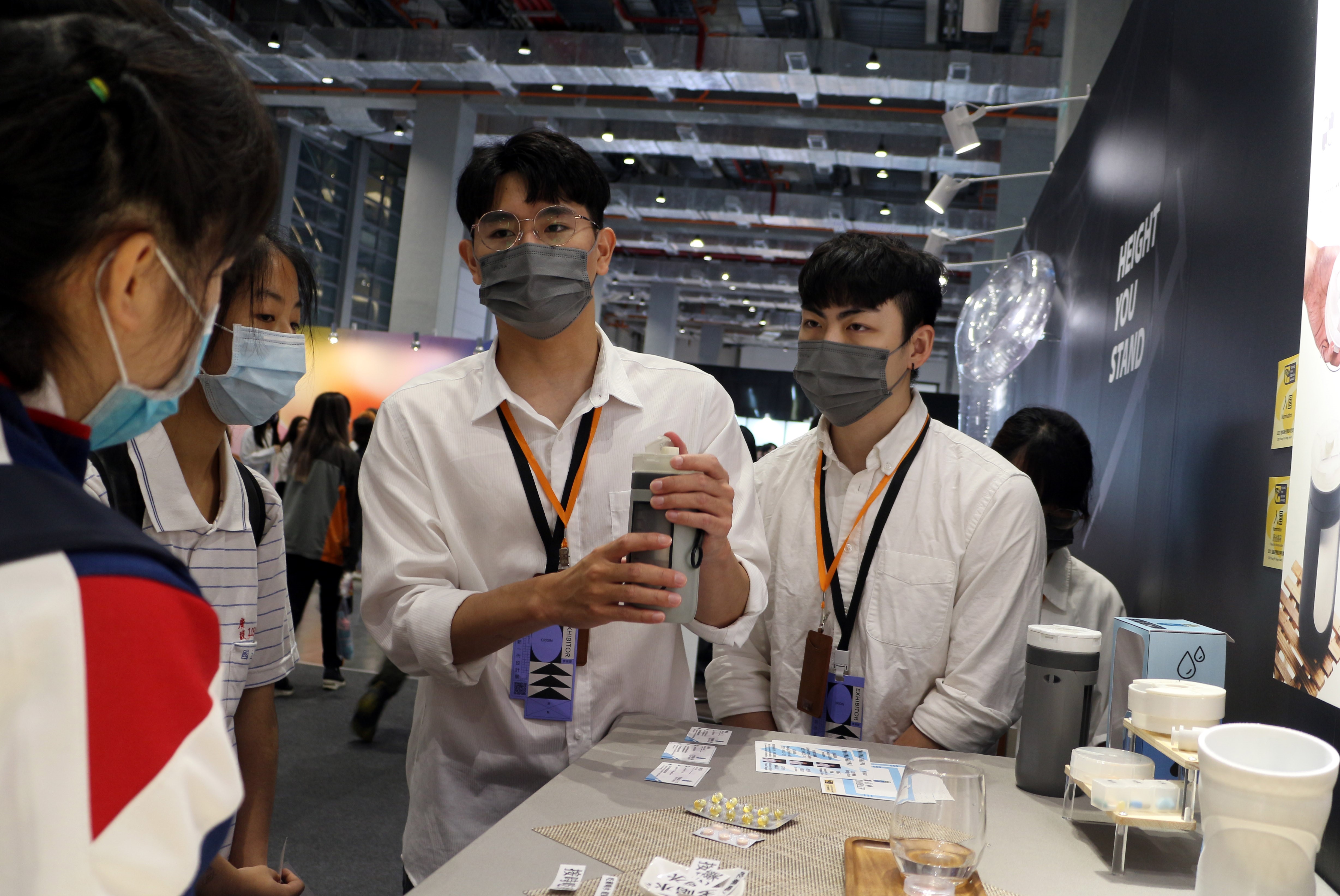 圖為亞大商設系鄭宇倫 (左1)、白翔元(左2)同學，在「2023新一代設計展」上，介紹獲獎作品「拾藥隨行杯」。