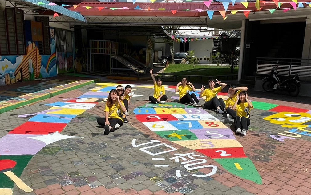 图为亚大幼教系同学，获邀在幼儿园地板上彩绘，留下印记。