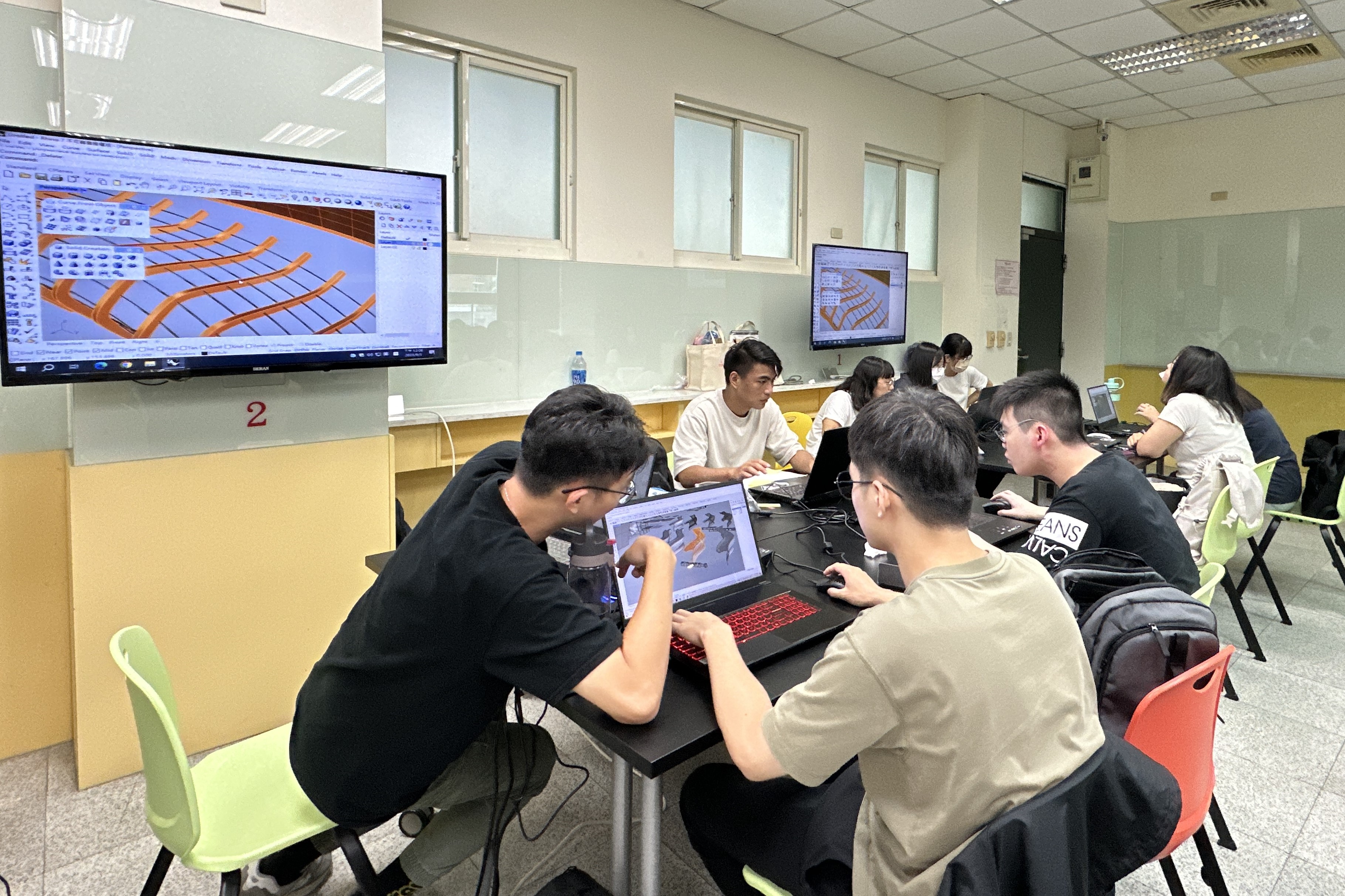 圖為亞大執行「偏鄉AI雙語學伴培育計畫」,「AI衍生設計工作坊」同學相互討論設計作品。