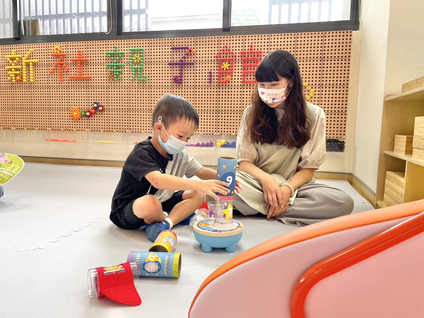 圖為新社親子館啟用，遊戲區教保員與幼兒互動。