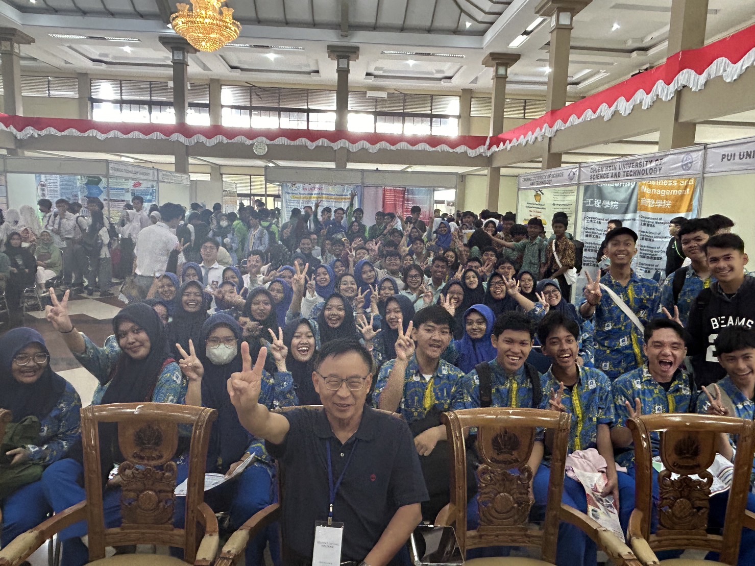 圖為「2023台灣高等教育博覽會」主辦單位、亞大國際學院長陳英輝(前)與現場參與的印尼高中生合影。