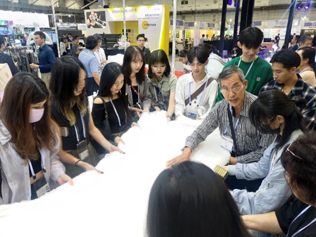 圖為在台北紡織展中，業者代表為亞大時尚系同學介紹新材料。