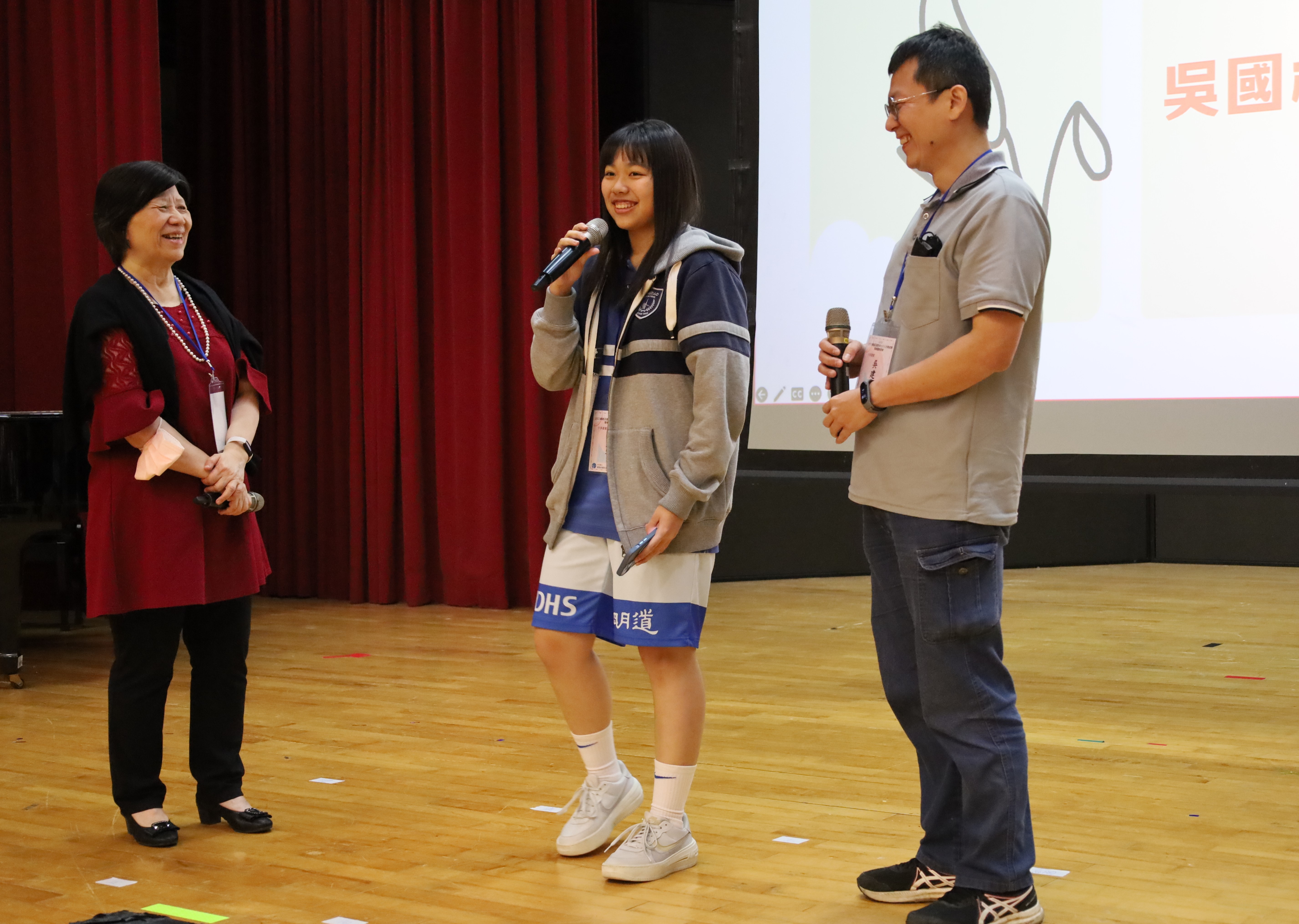 图为参加营队的高中生吴冠宁(中)，和爸爸吴建庆(右)上台分享，一起参加亚大营队，学习健康上网后，亲子关系和生活上的改变，亚大副校长柯慧贞也称讚她的整体表现佳。