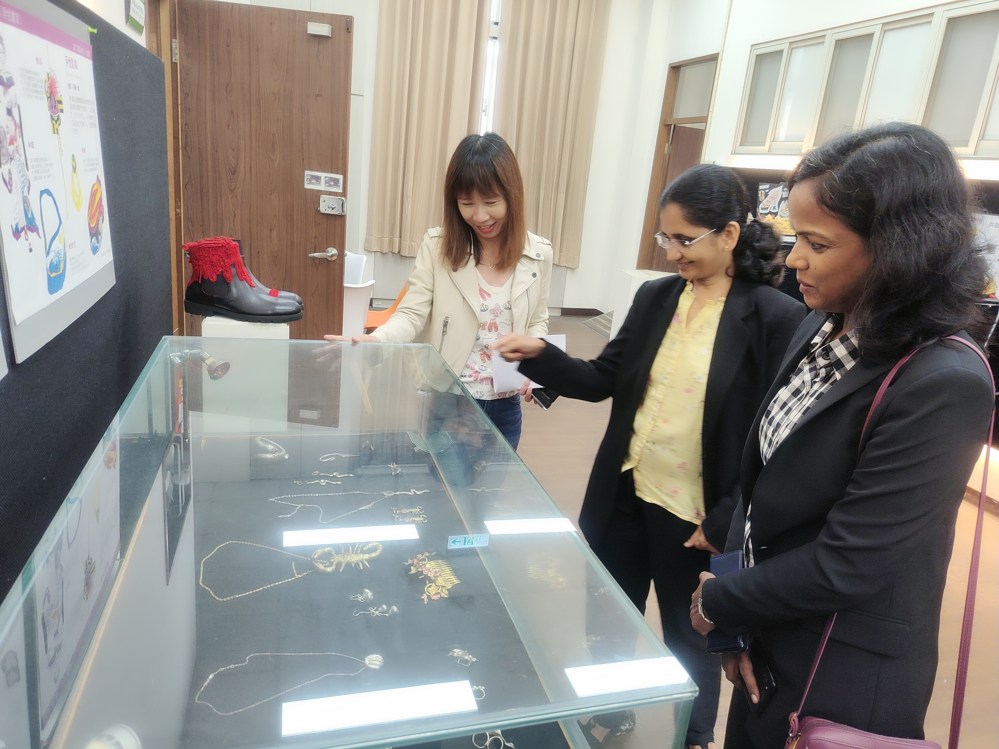 圖為(由左而右)亞大時尚系黃明媛老師，向印度韋洛爾理工大學清奈校區Dr. John Sahaya Rani Alex 、Dr. Jeetashree Aparajeeta，介紹該系師生的服飾作品。