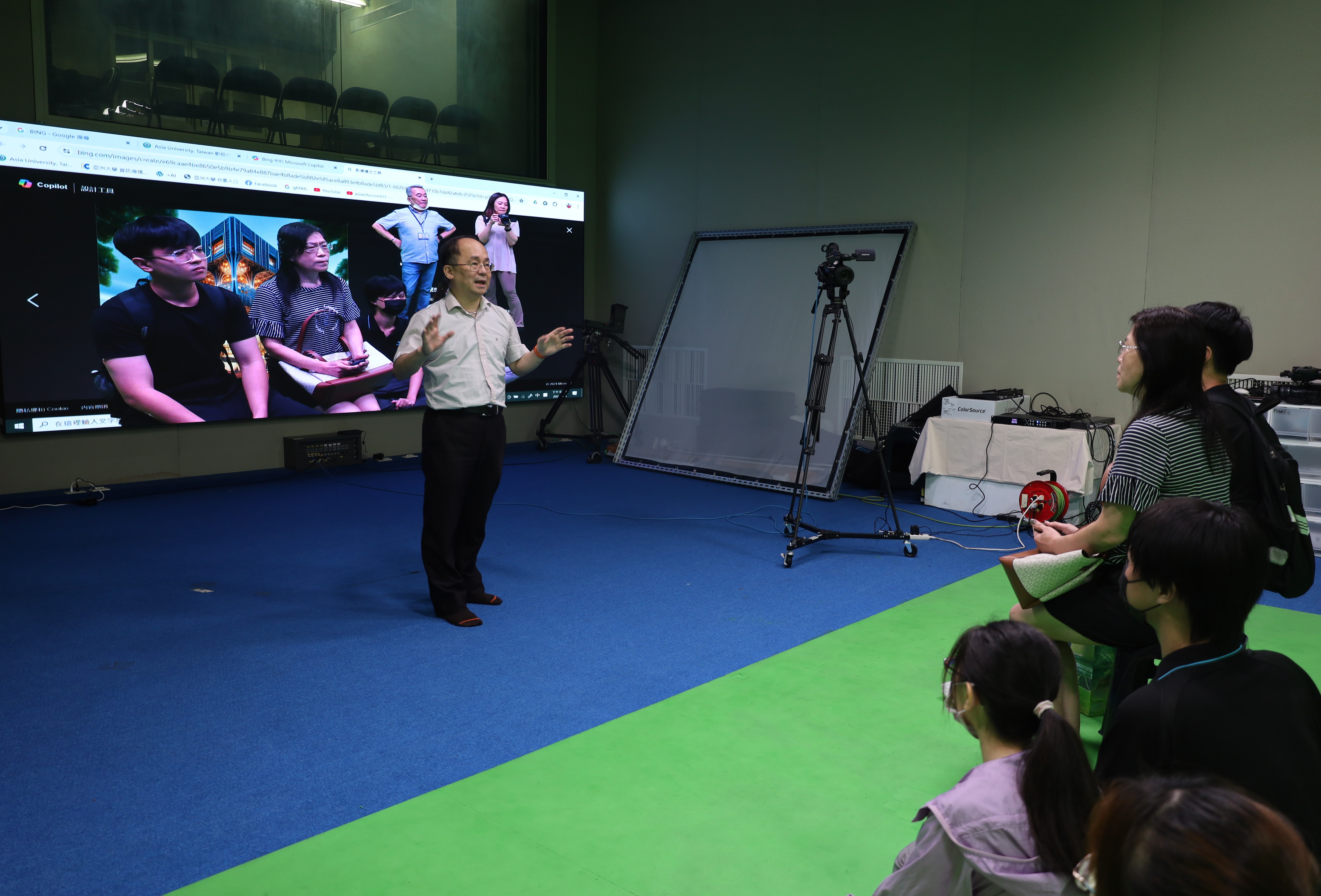 圖為亞大資傳系主任陳士農(左)，說明虛擬攝影棚的應用。