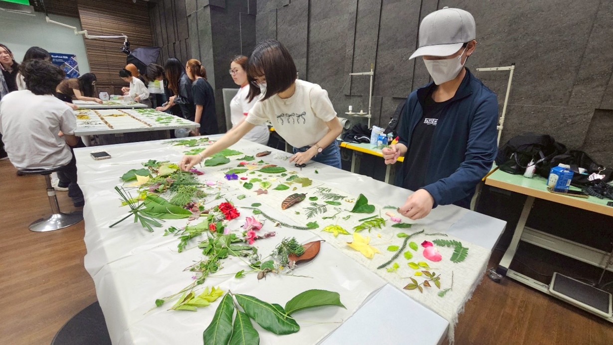 移印染實務操作時,亞大時尚系同學將摘取的葉片、花瓣,依次在羊毛纖維布料上排列。