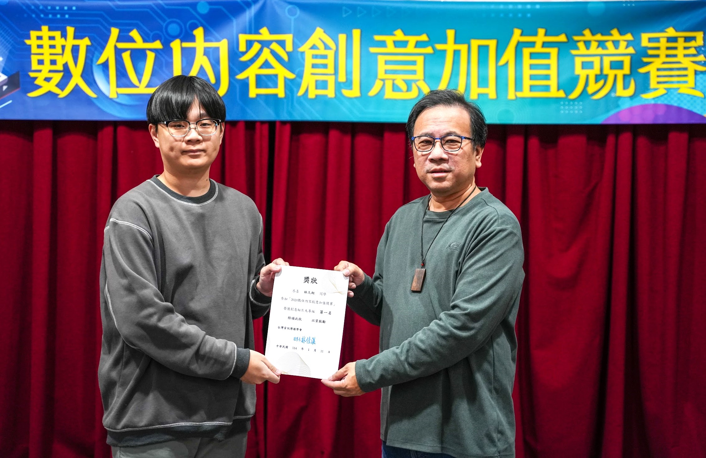 圖為台灣資訊傳播學會理事長林佳漢（右），頒獎給獲大專院校首獎的亞大資傳林久翔同學(左)。
