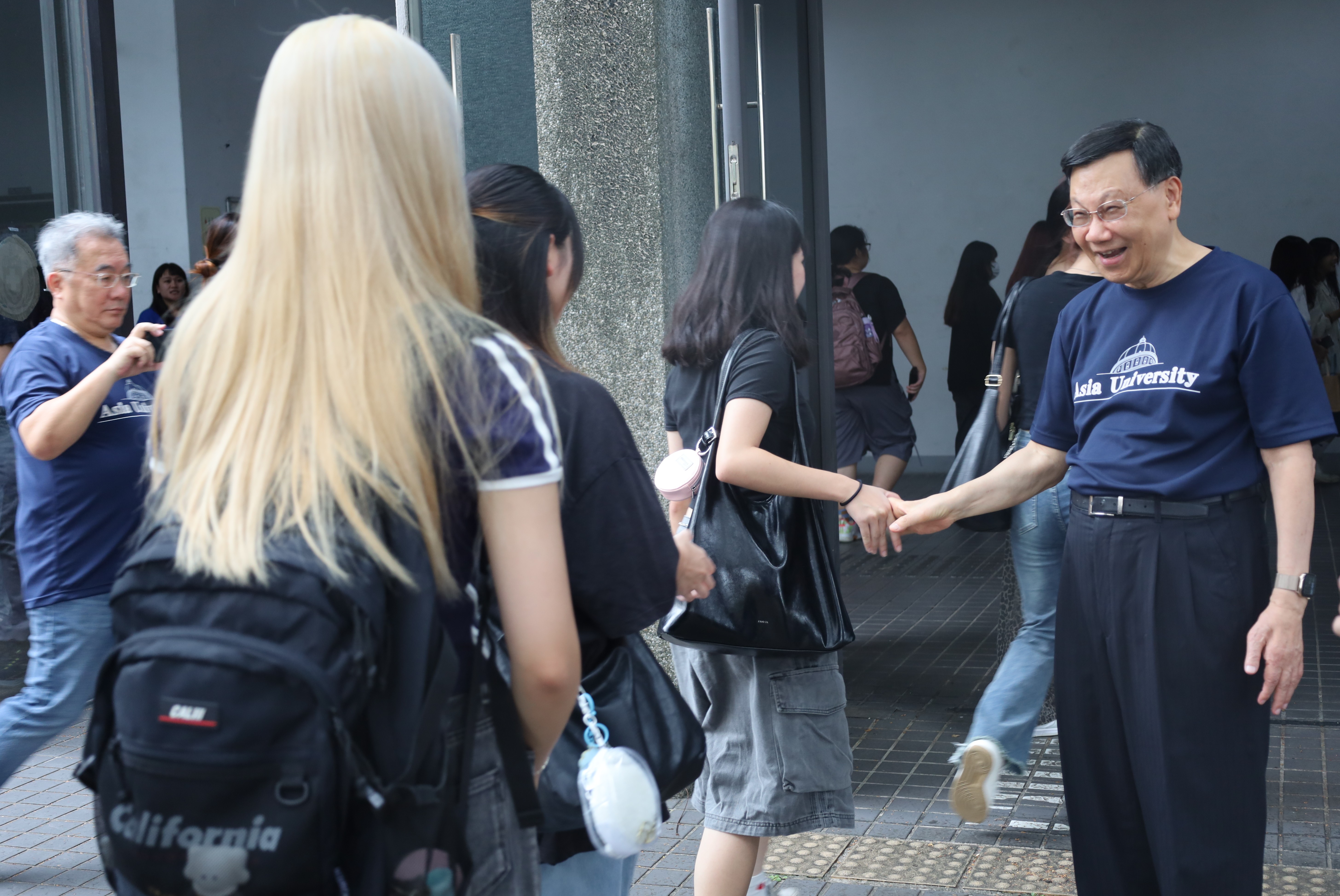 許多新生在始業式時,和亞大校長蔡進發(右)擊掌、握手。