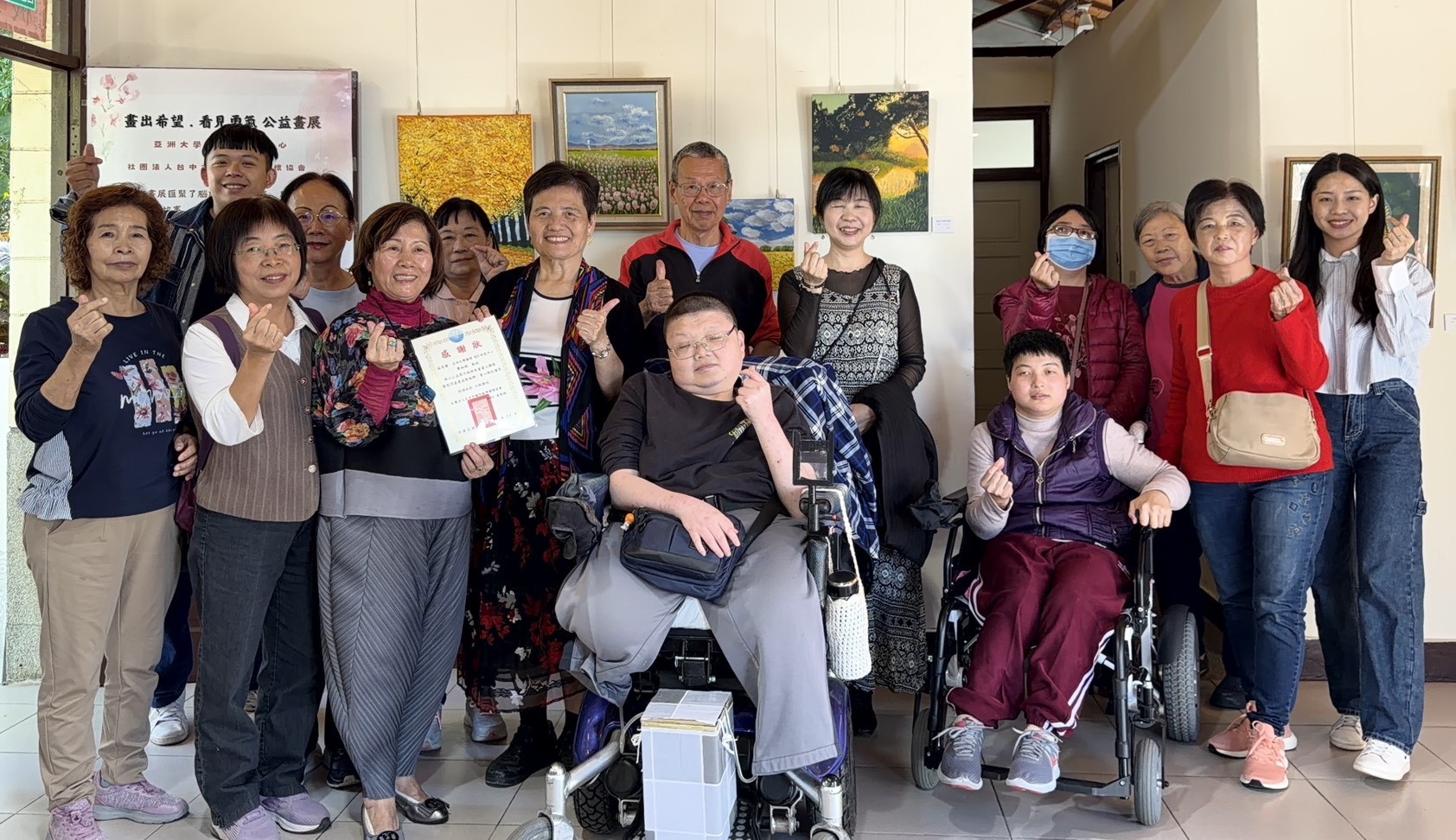 亞大人文社會學院院長廖淑娟(前排左4)、台中市腦性麻痺關懷協會執行長林瑞碧(前排左3)，和參與腦麻畫家、家屬、亞大師生等合影。