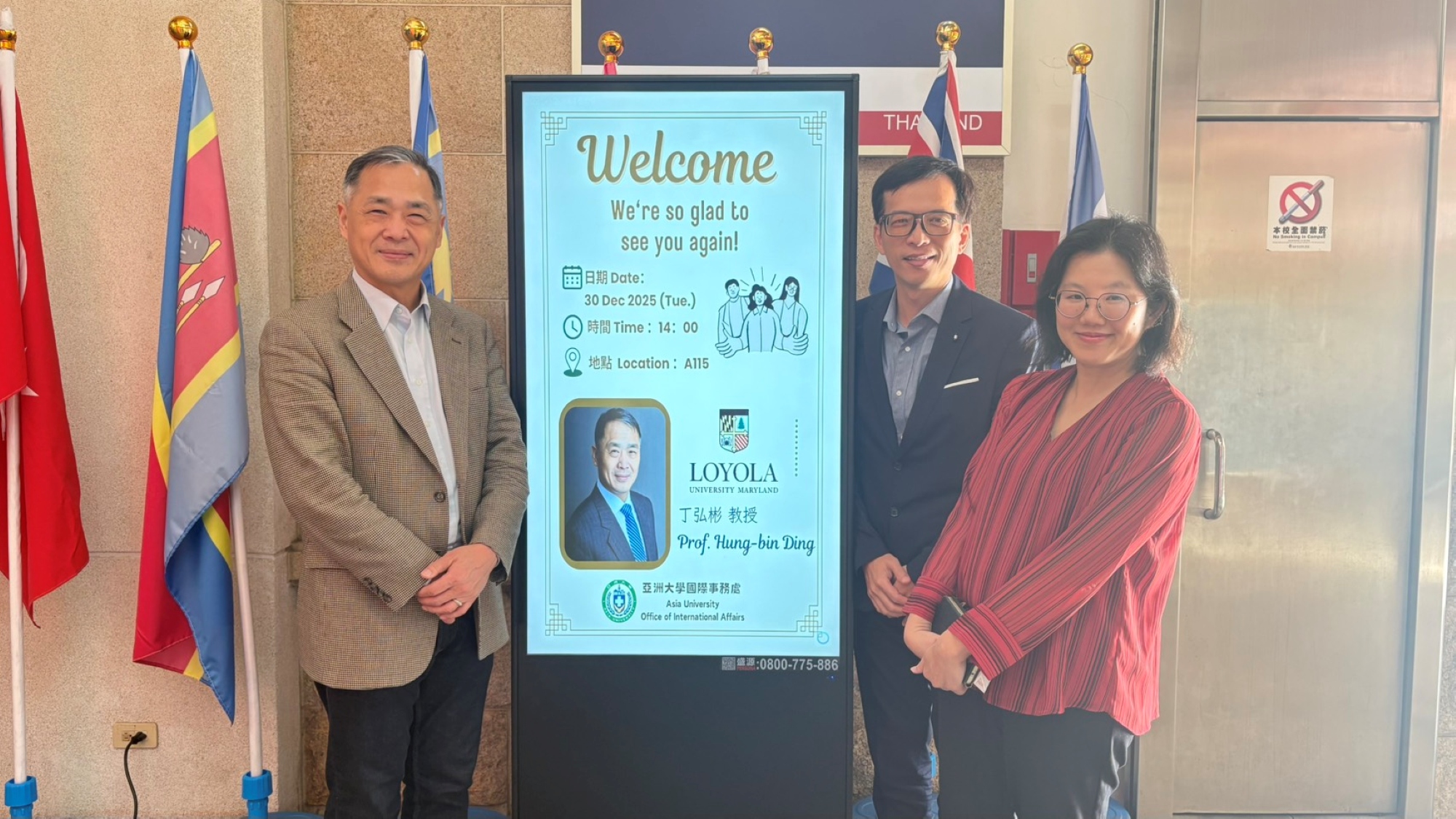 姊妹校美國馬里蘭羅耀拉大學(Loyola University Maryland)商學院副院長丁弘彬(左)與亞洲大學國際處副國際長尤啟良(右1)以及華語文中心主任毛元臻(右2)歡迎海報前合影。