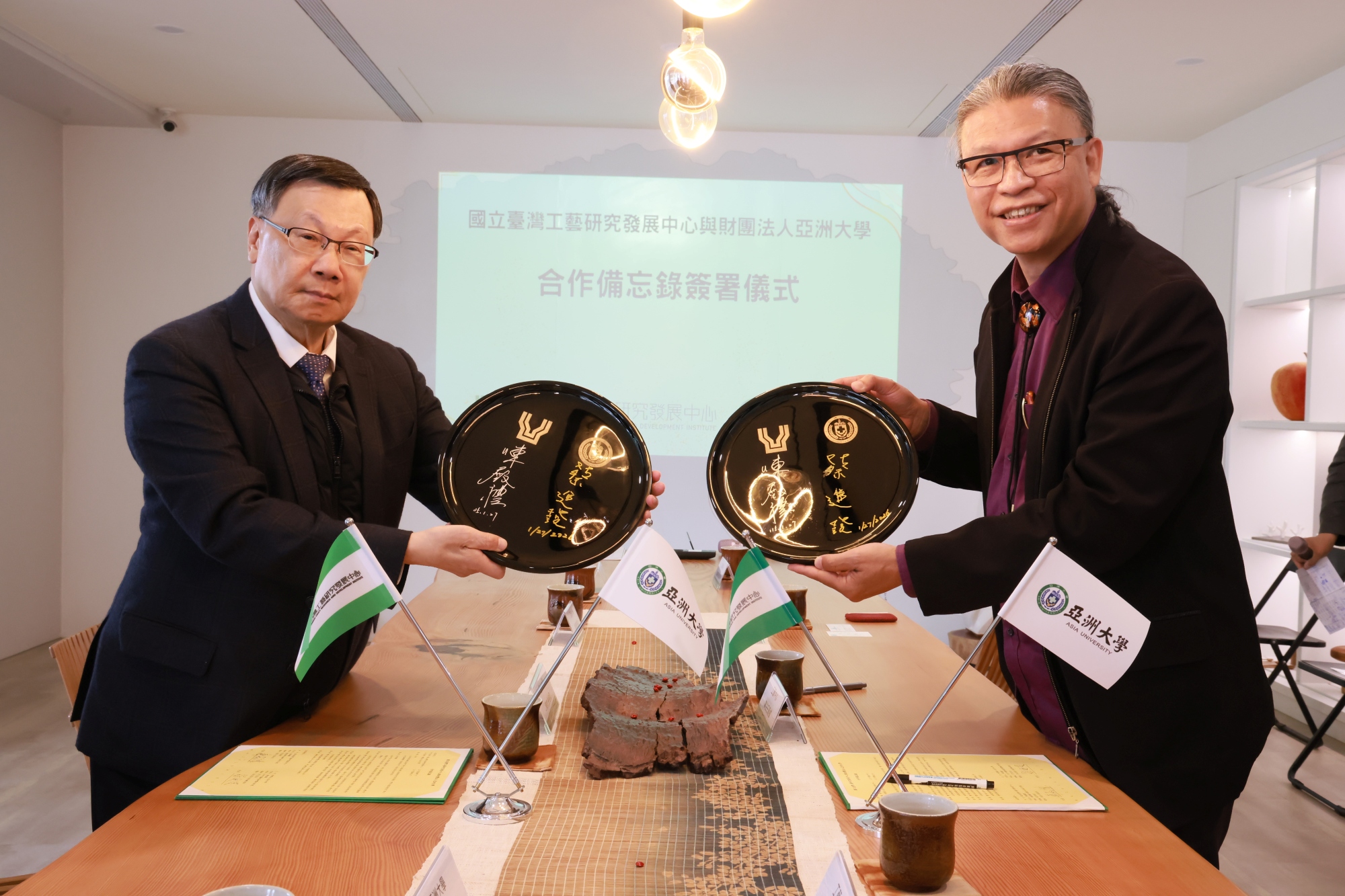 亞洲大學校長蔡進發 (左)與工藝中心陳殿禮主任共同於漆盤上簽署合作備忘錄。