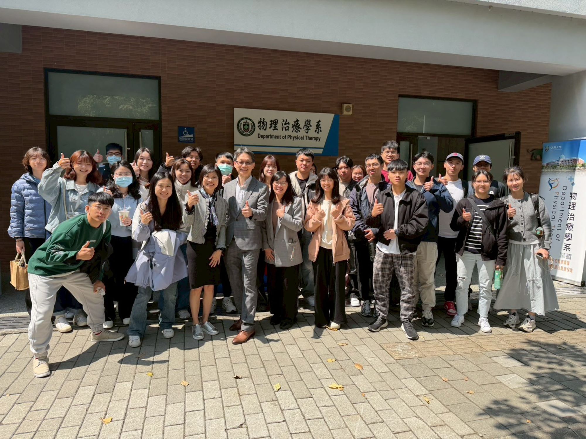 亞大物治系舉辦「第三屆系友回娘家」活動，近三十位畢業系友與師長於系館前開心合影，展現物治大家庭的溫暖凝聚力。