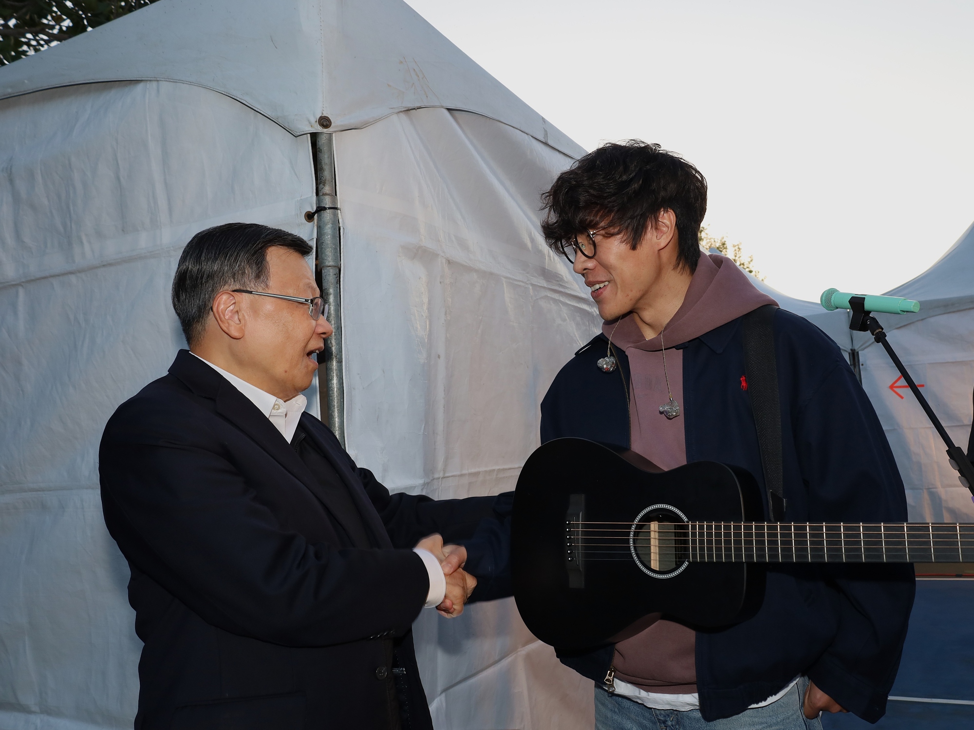 亞洲大學校長蔡進發(左)親自到場支持,並於後台與開場嘉賓盧廣仲(右)熱情握手致意。