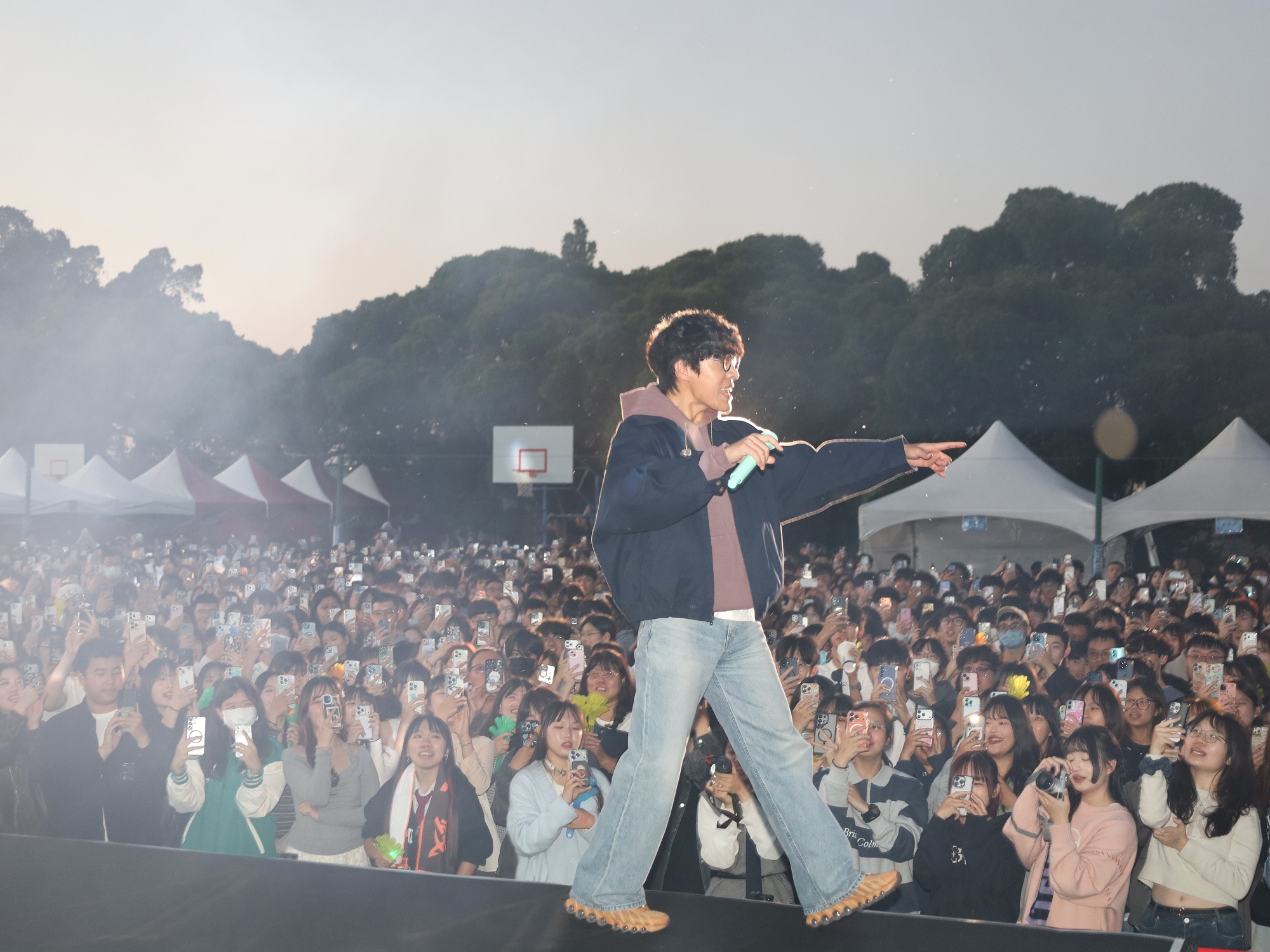 盧廣仲熱情地與台下學生指引互動,身後是數千名亞大師生點亮手機閃光燈匯聚而成的浪漫星海。