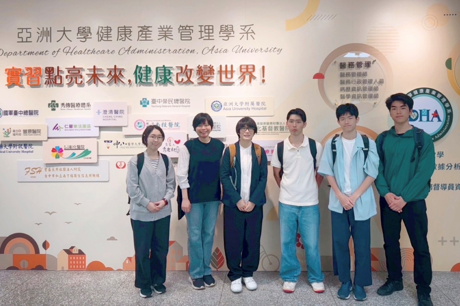 神戶大學師生與亞大健管系林冠含副教授(左二)於學系看板前大合照。林副教授與身旁的大一學生(左一)愉快互動,神戶大學余玟欣助理教授(左三)亦一同見證兩校師生的專業交流。