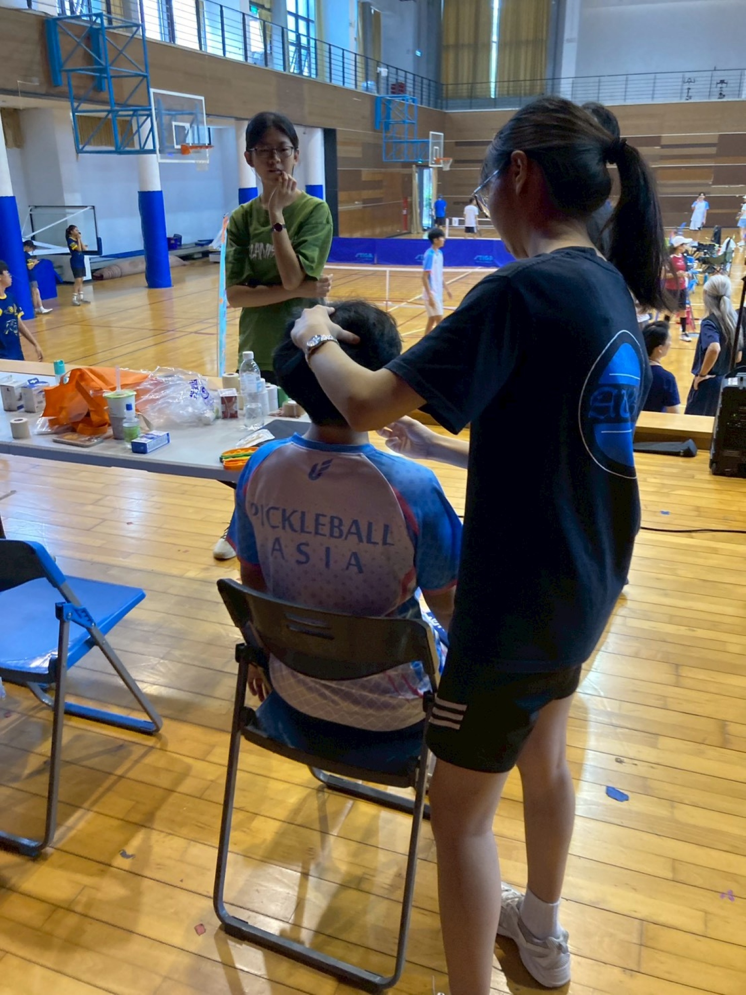 亞大物治系志工學生於場邊防護站,專注為參賽選手進行運動傷害評估。