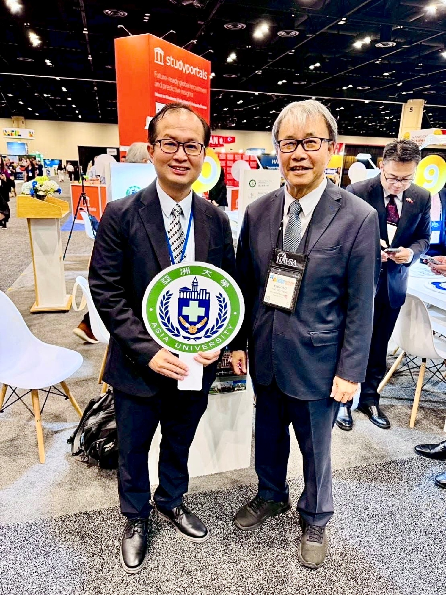 亞洲大學副校長黃俊杰(左)與教育部長鄭英耀(右)於 NAFSA 年會展場合影。
