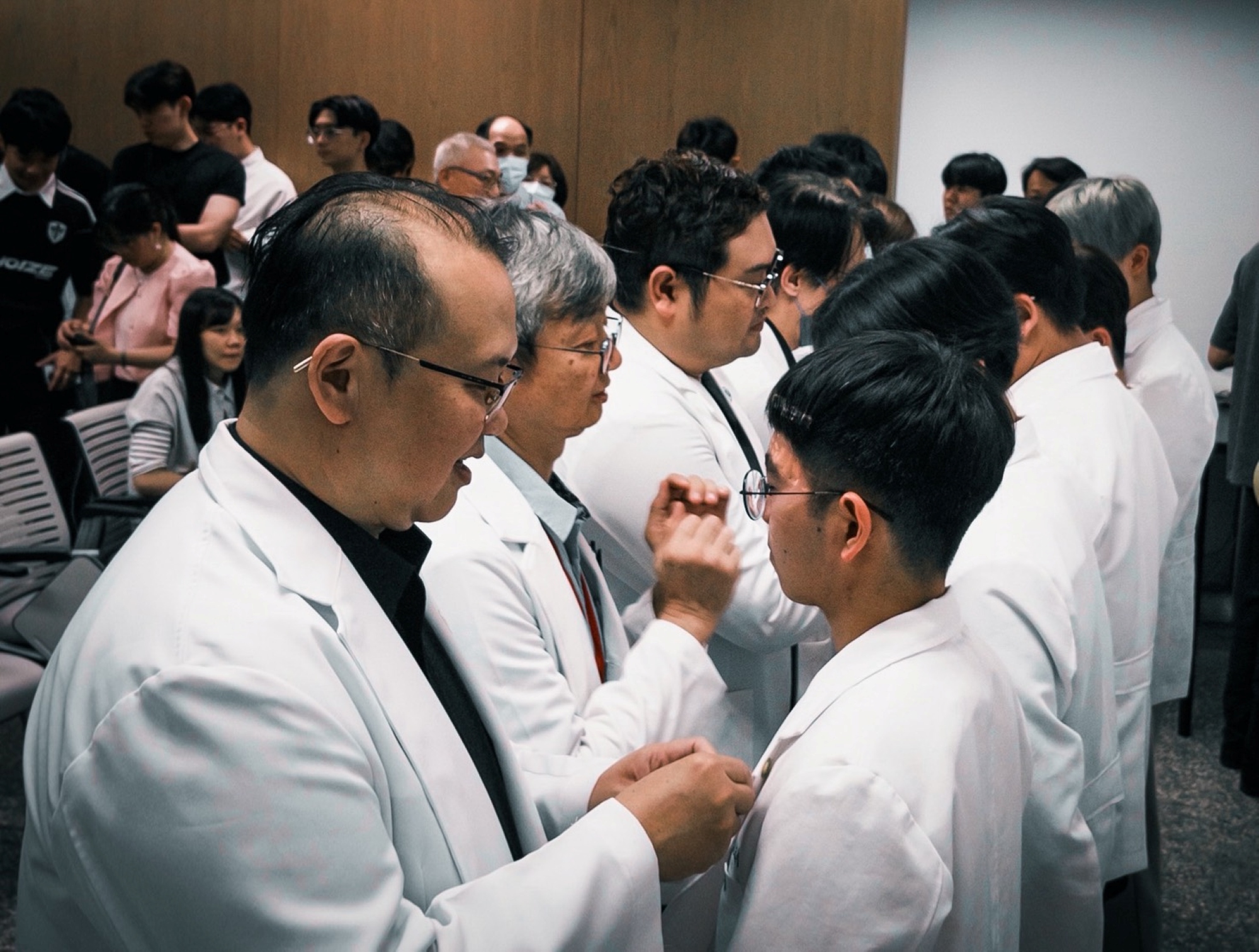 在授袍儀式中,師長親手為學生佩戴象徵亞大視光精神的系徽,傳承專業與責任。