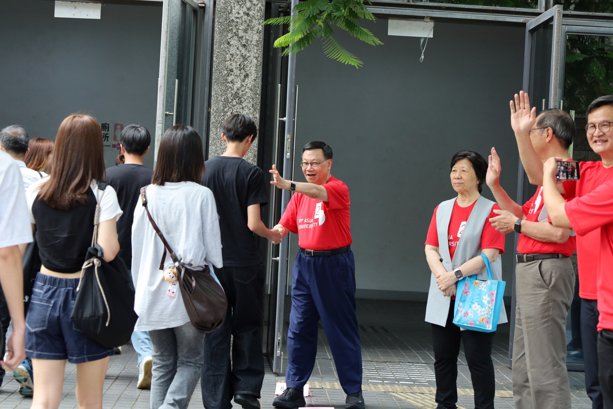 校長與主管在體育館入口親切迎接新生,以握手、揮手歡迎新鮮人報到。